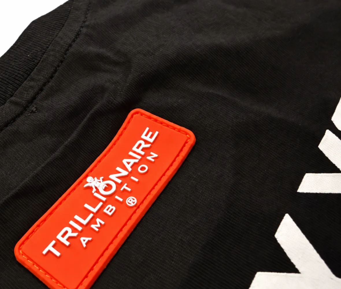The orange-red rubber logo patch, stitched to the black tee, with Trillionaire Ambition raised in white