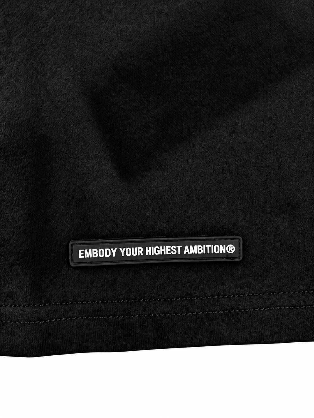 Close-up of the black rubber hem patch reading Embody Your Highest Ambition®